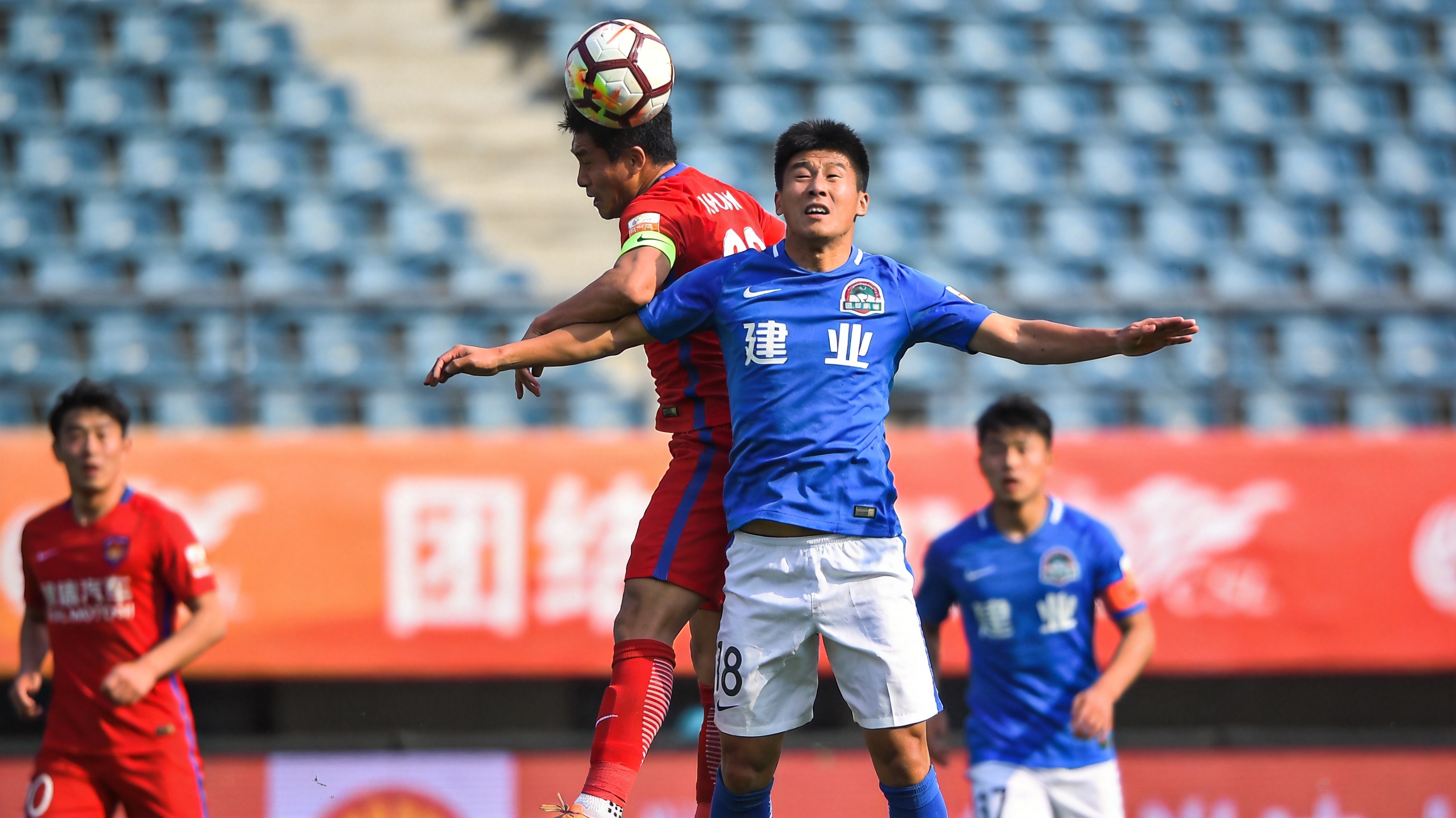 足球赛场激烈比赛瞬间，球员争顶头球